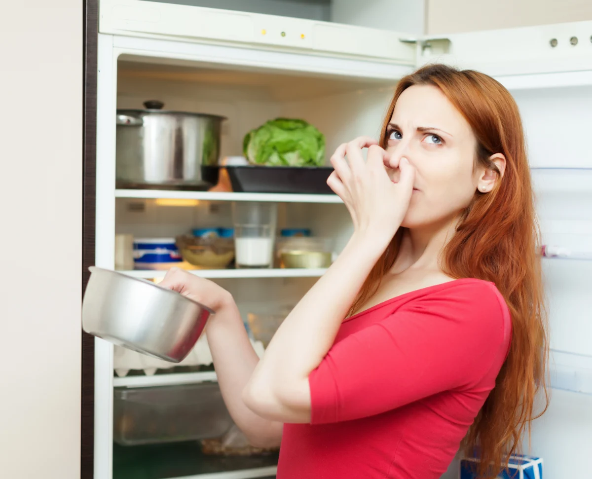 a woman noticing bad odor from fridge