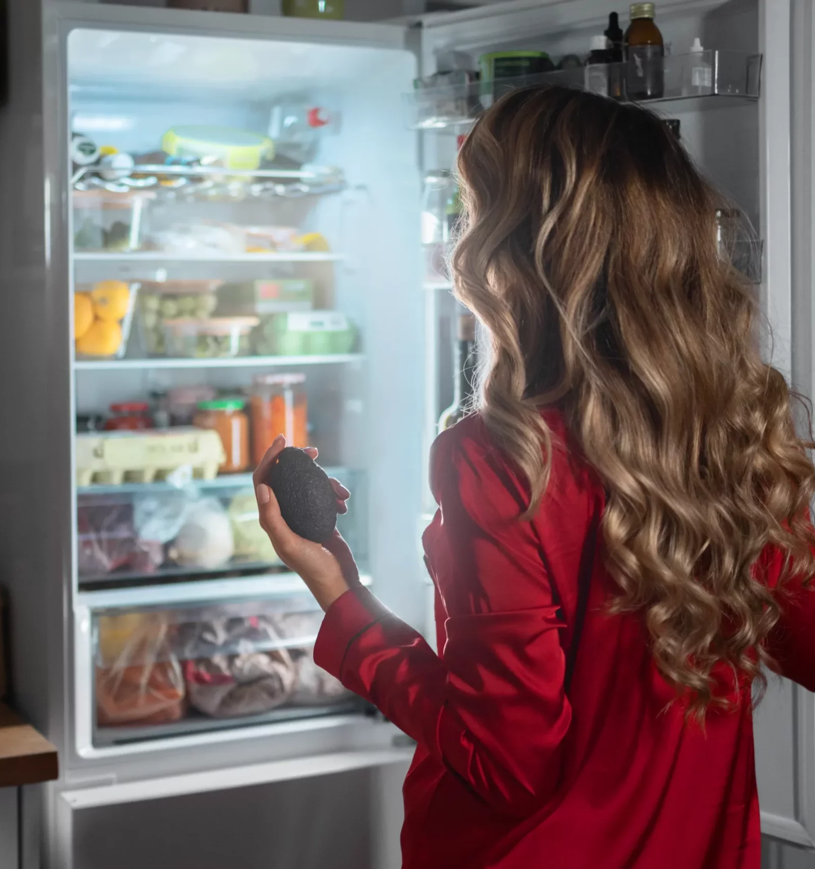 A woman opening the door of her cold freezer